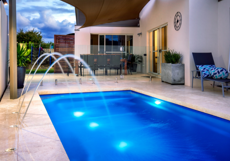 Casa con piscina con iluminación de exterior.